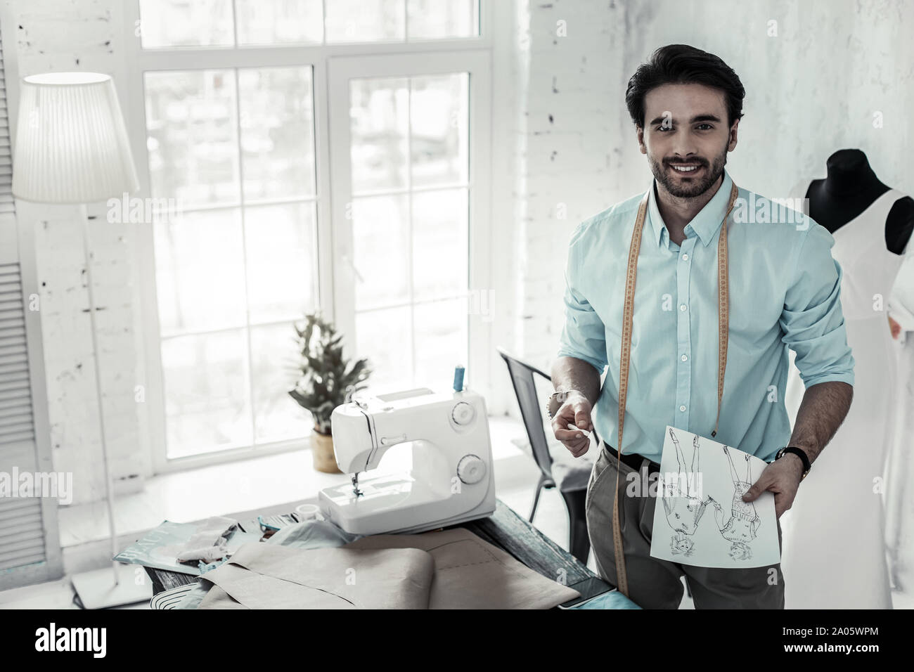 Positive delighted tailor showing his professional workshop Stock Photo ...