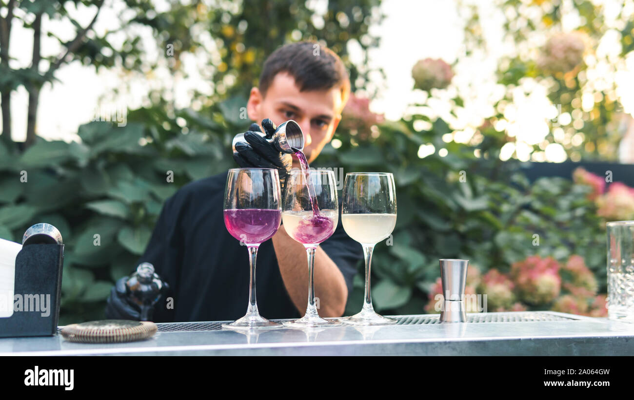 Bartender making alcoholic cocktail, summer cocktail outdoors. Colorful cocktail on top of the bar. Summer refreshment drinks. Light pink rose cocktai Stock Photo