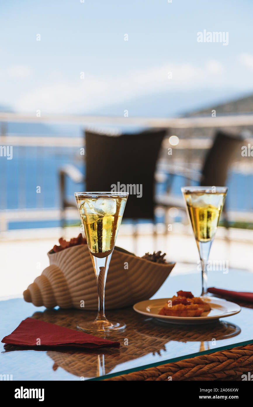 Two cold glasses of iced tea, white wine with ice cubes and a greek traditional snack with a Greek Fava on a table at a hotel resort. Stock Photo