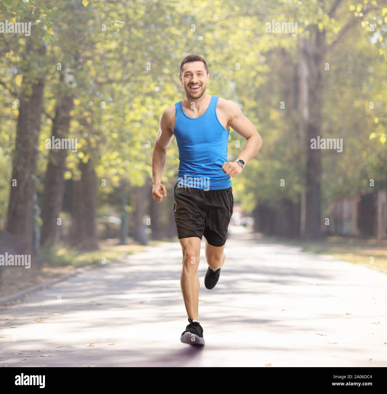 Full length portrait of a young guy jogging in a park and smiling Stock Photo