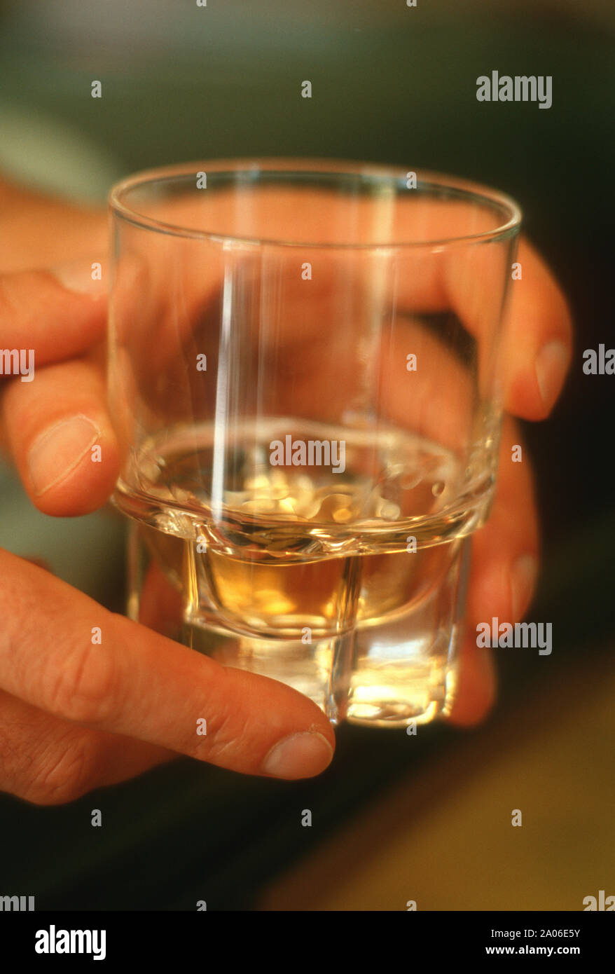 Man's hand holding a glass of hard liquor, female alcoholism Stock Photo