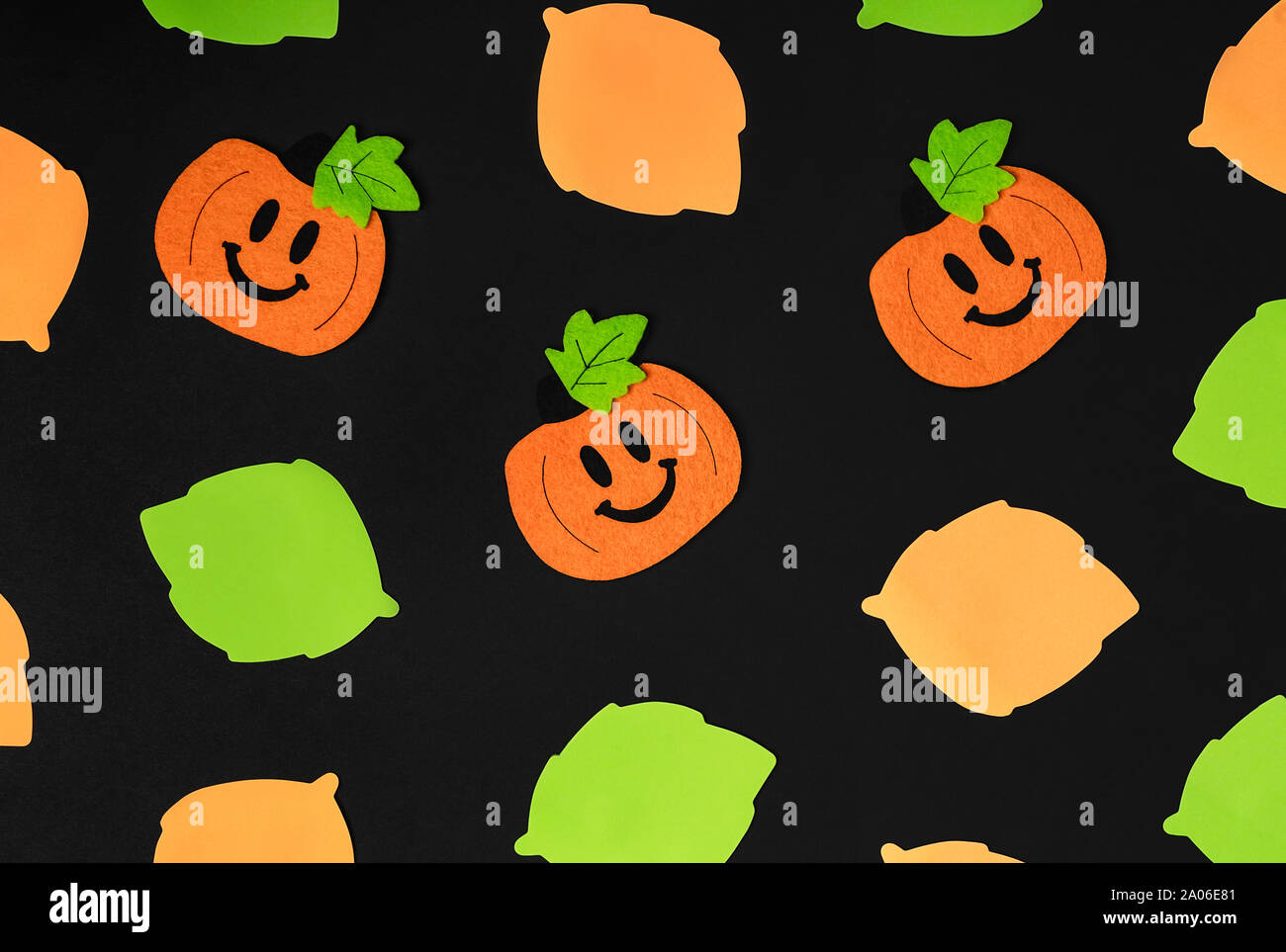 Background of halloween theme decorations. Toy pumpkins and assortment of leaves on black backdrop. Flat lay style. Copy space. Copy space. Flat lay s Stock Photo