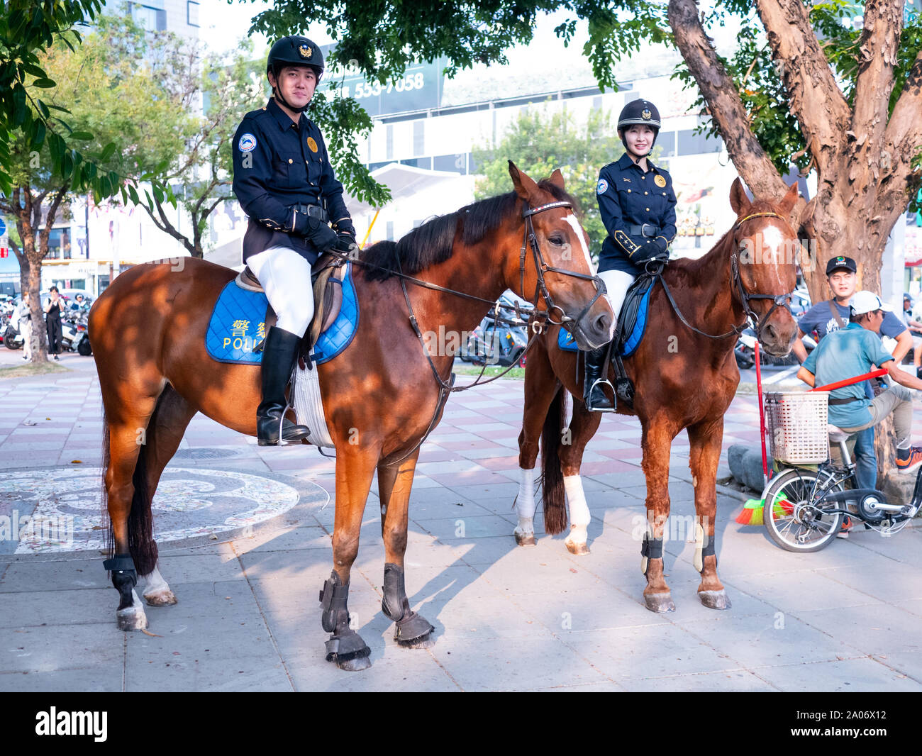 Kaohsiung, Taiwan: Taiwanese horse mounted police. Two Police officers riding brown horses in Kaohsiung central park. Male and female Police Officers Stock Photo