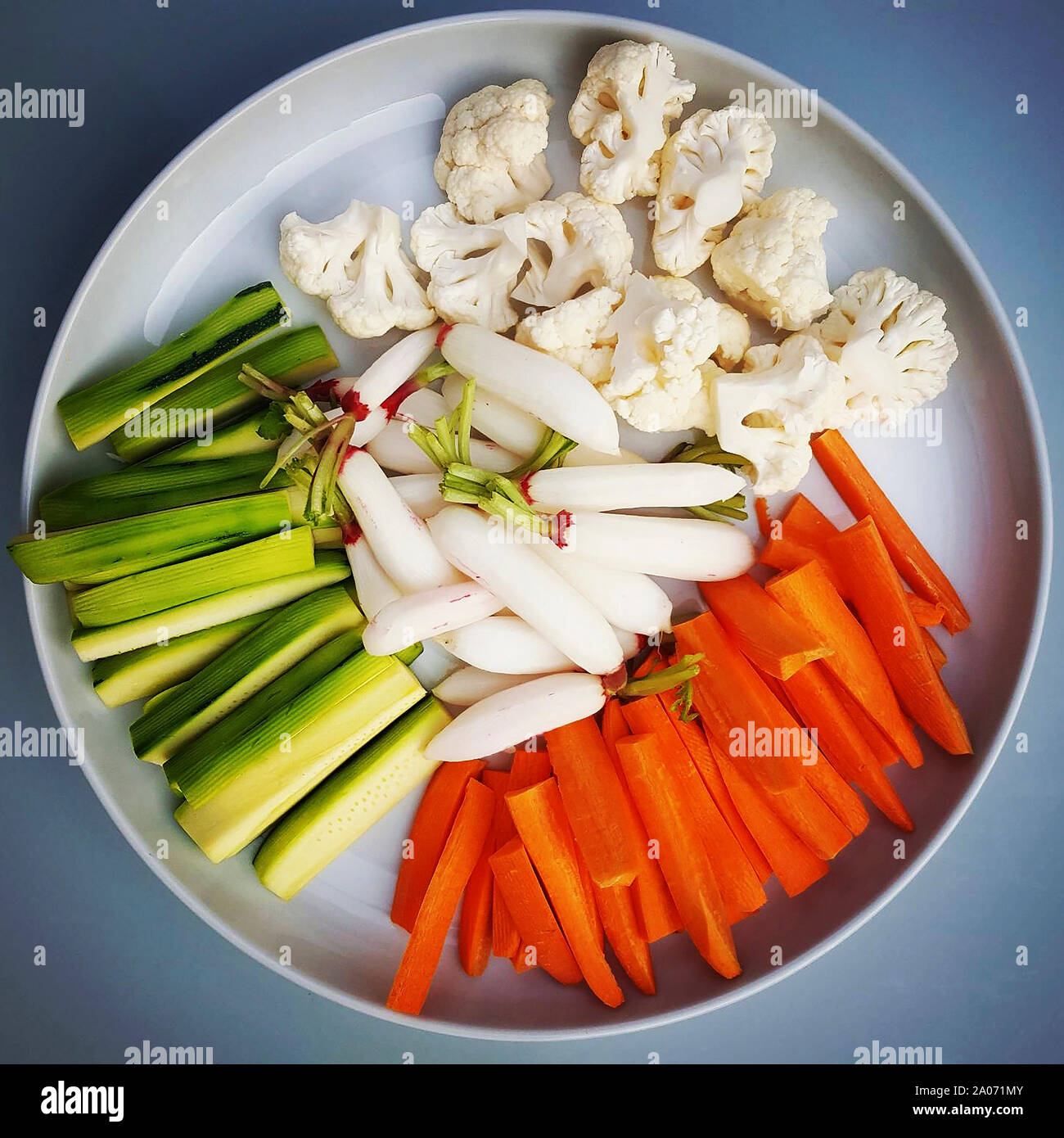 Closeup of cauliflowers carrots and cucumbers in a plate on the table under the lights. Stock Photo