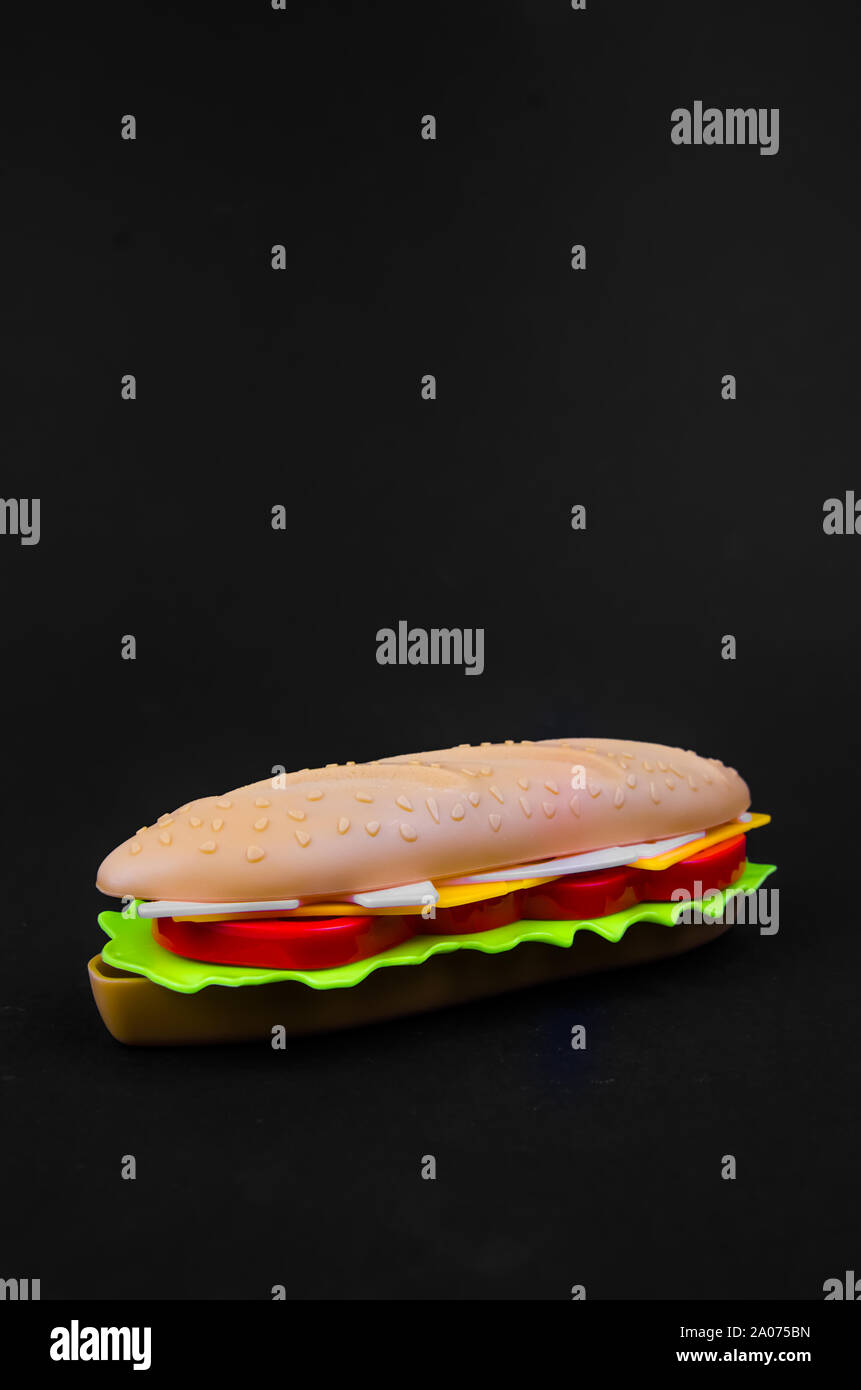 fast food. plastic hot dog on a black background. copy space Stock