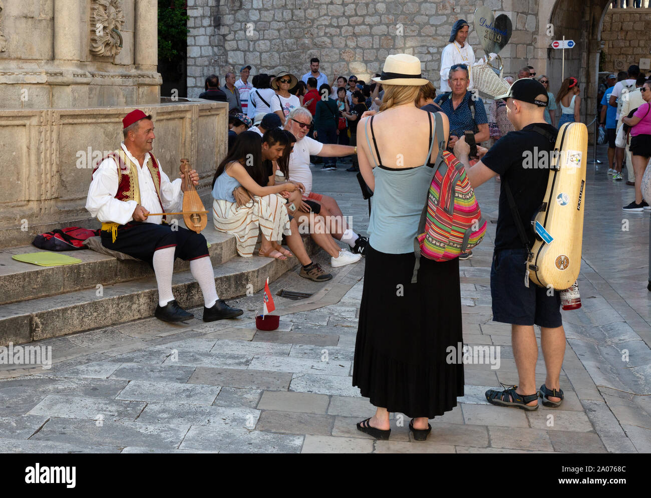 Dubrovnik busker - street entertainer dressed in traditional clothes playing a musical instrument; the Onofrio fountain, Dubrovnik old town, Croatia Stock Photo