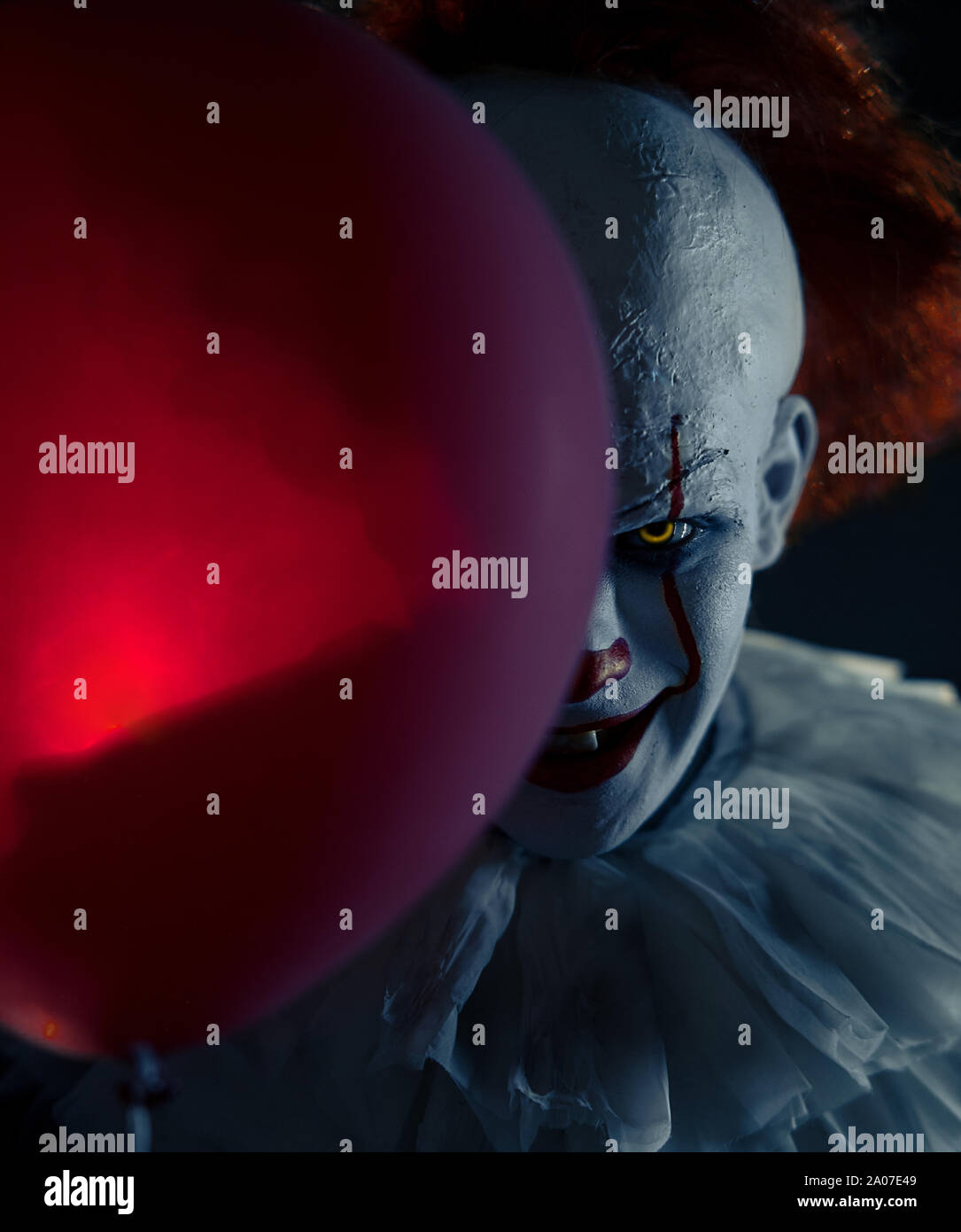Portrait of a clown with red balloon in his hand with backlight. Stock Photo