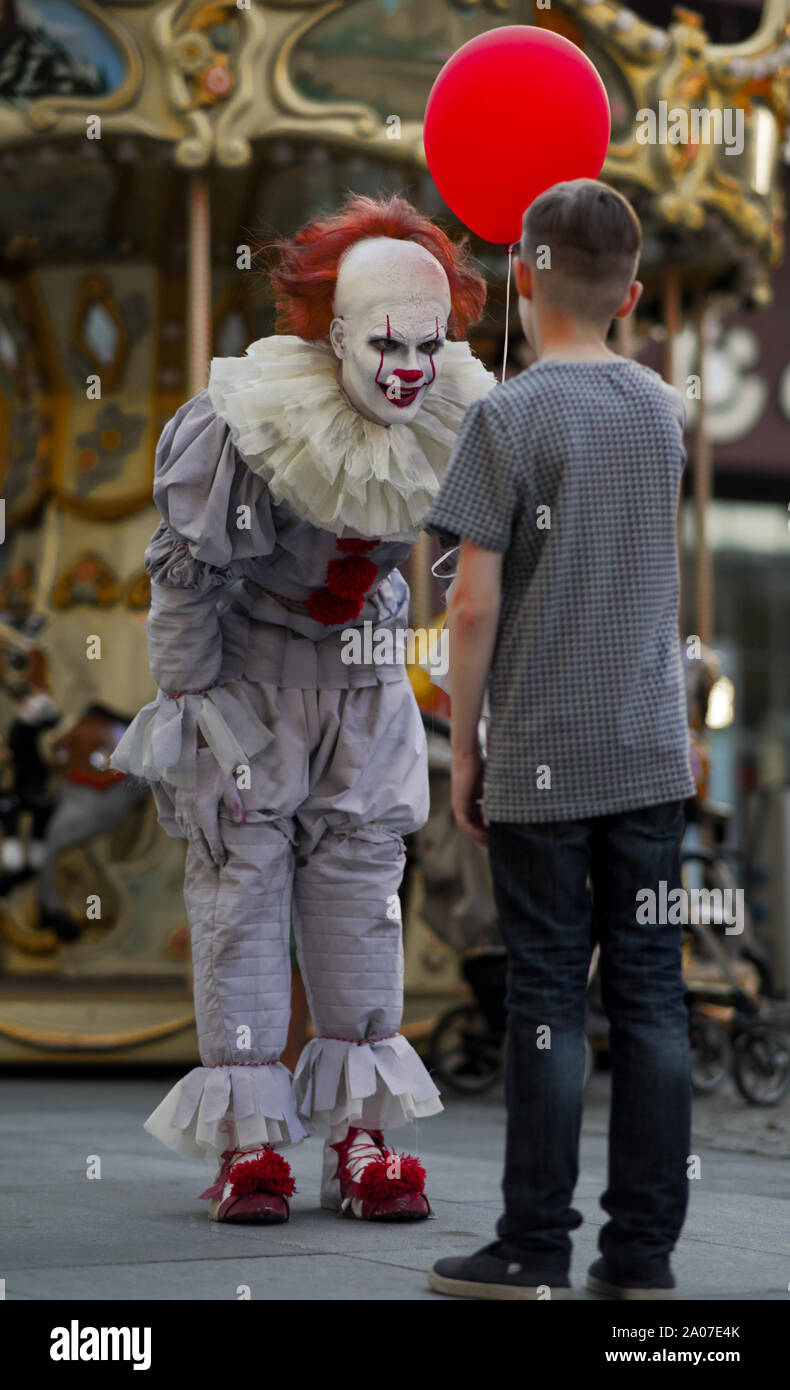 A man in the image of a clown shakes hands with a boy and holds red balloon  in his hand Stock Photo - Alamy