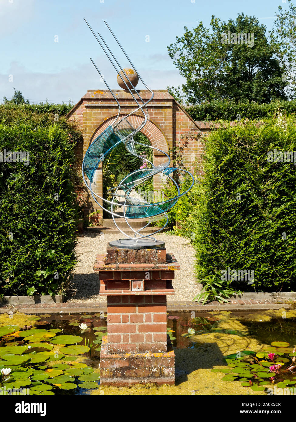 East Ruston Old Vicarage Gardens - sculpture, arch and hedges enclose the ornamental pond in an old-established area. Stock Photo