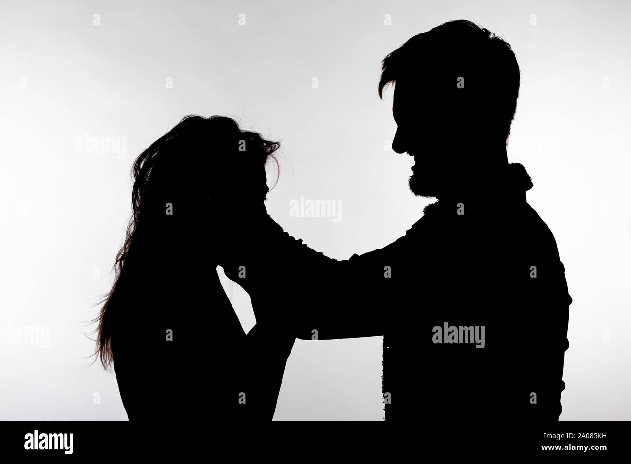 Domestic violence and abuse concept - Silhouette of man beating defenseless woman. Stock Photo