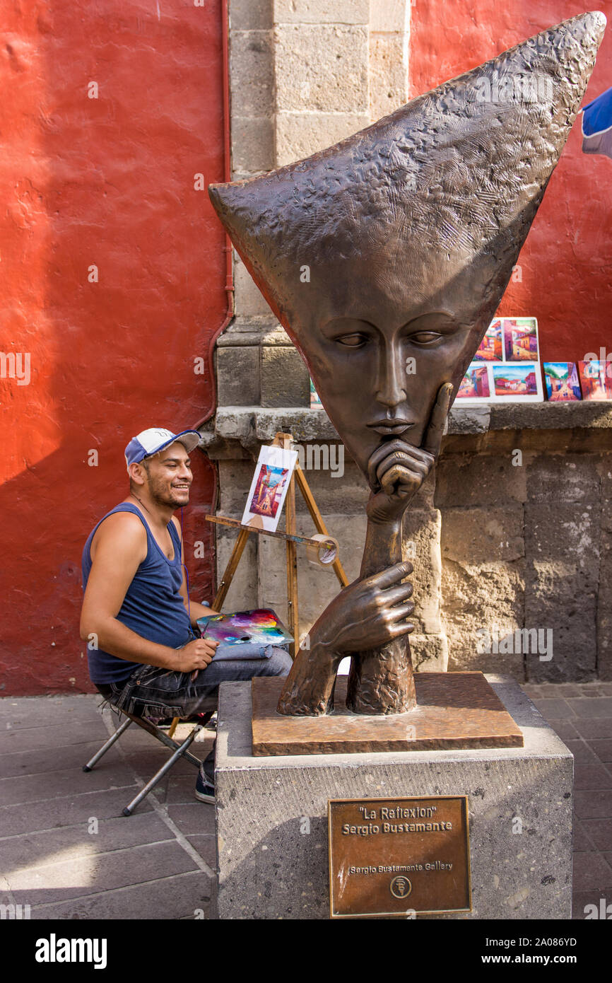 Sidewalk artist beside artwork sculpture at the Sergio Bustamante Gallery, Tlaquepaque, near Guadalajara, Jalisco, Mexico. Stock Photo