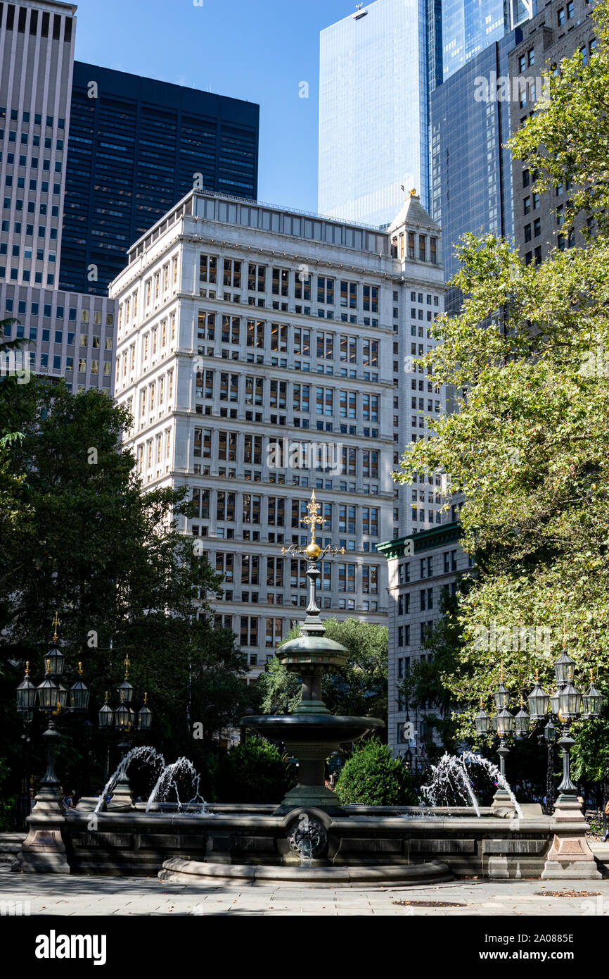 Bäume, Hochhäuser, Brunnen und Laterne im City Hall Park von NYC am Morgen Stock Photo