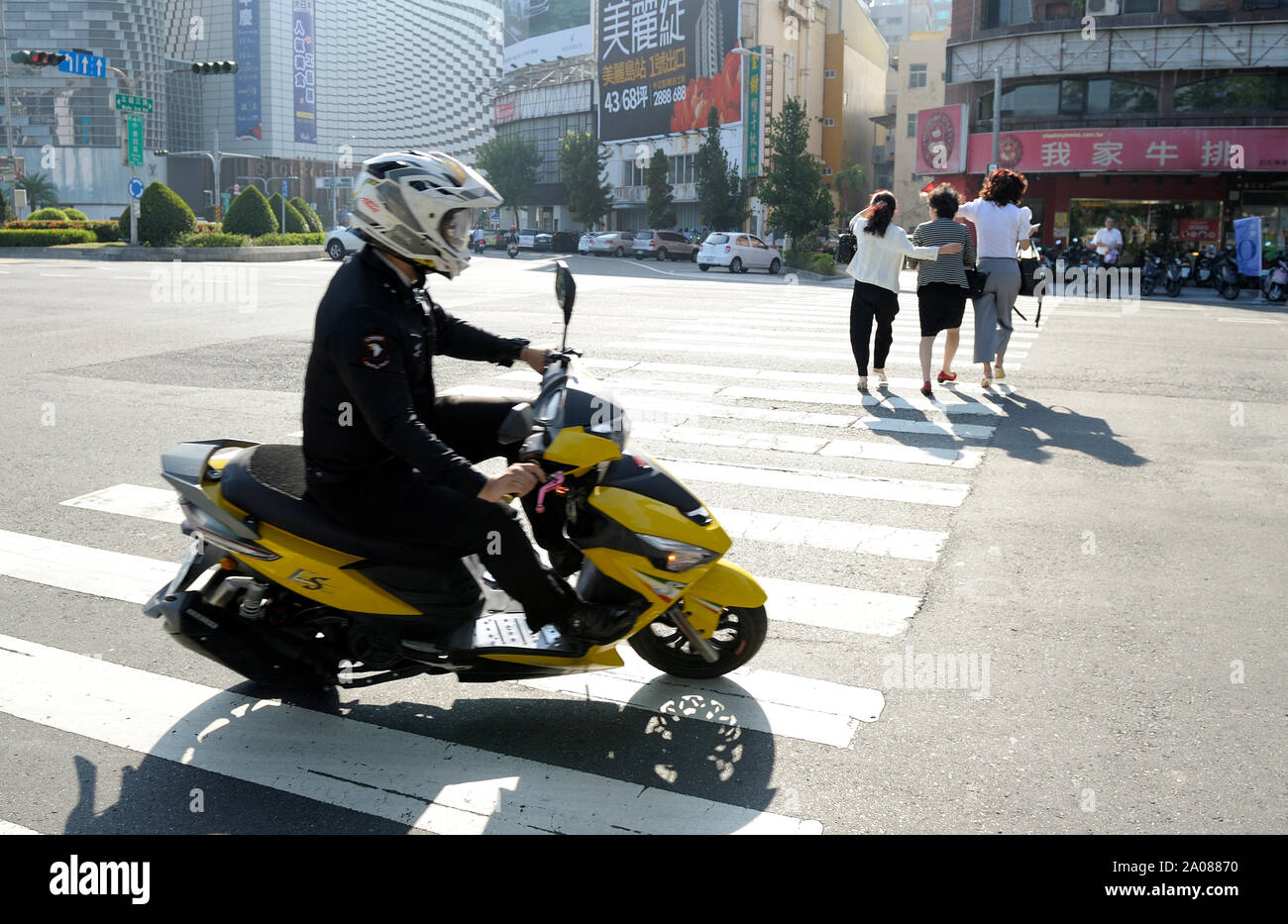 A fast scooter rider is looking at three women (Kaohsiung, Taiwan). Stock Photo