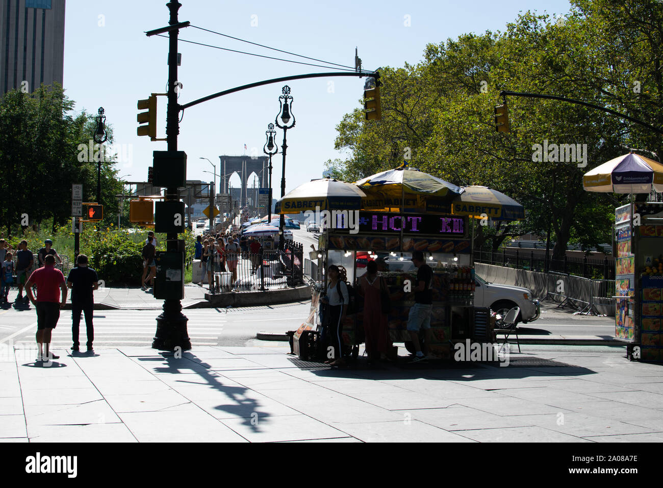 Blick auf die Brooklyn Bridge im Gegenlicht von der Centre Street aus aufgenommen. Menschen sind als Silhouetten zu erkennen. Im Vordergrund auf dem B Stock Photo