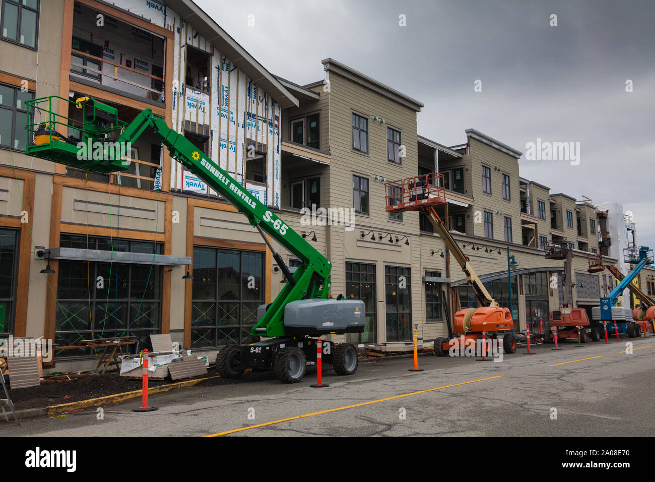 Several man-lifts being used on the exterior of a new building under construction in Steveston British Columbia Canada Stock Photo