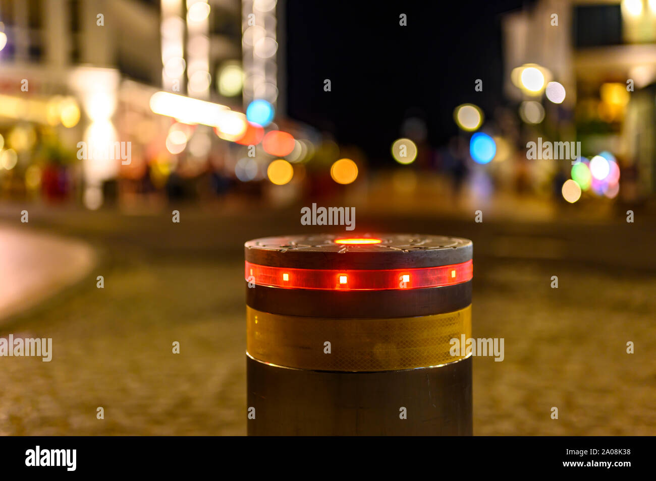 A retractable bollard with a red warning light as a barrier to a pedestrian  area at night in Bansin, Germany. In the background you can see points of  Stock Photo - Alamy, image size:1300x954