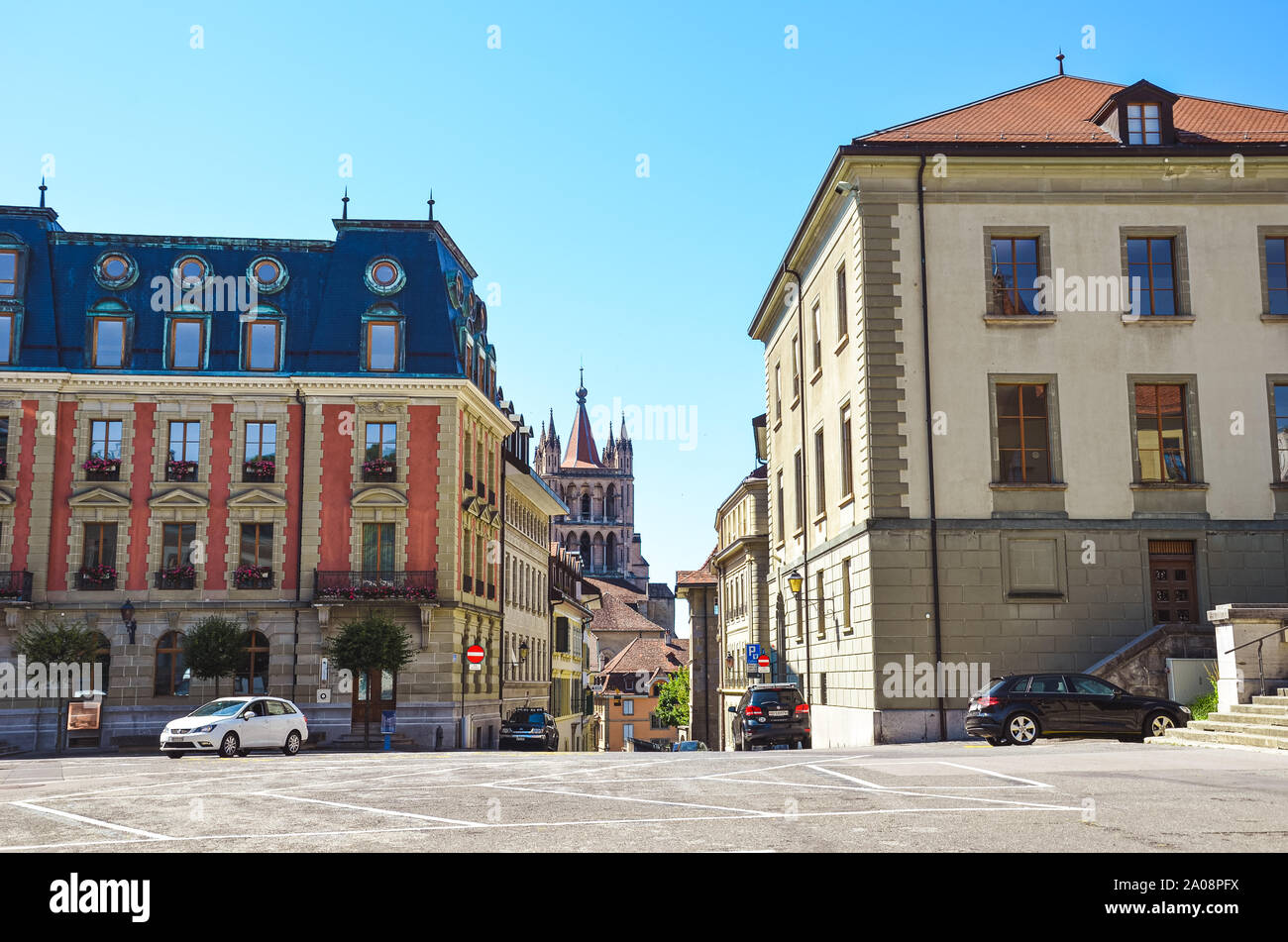 Lausanne, Switzerland - August 11, 2019: The old town of the French-speaking Swiss city with a famous Notre Dame Cathedral in the background. Historical buildings, cars on the road. Empty street. Stock Photo