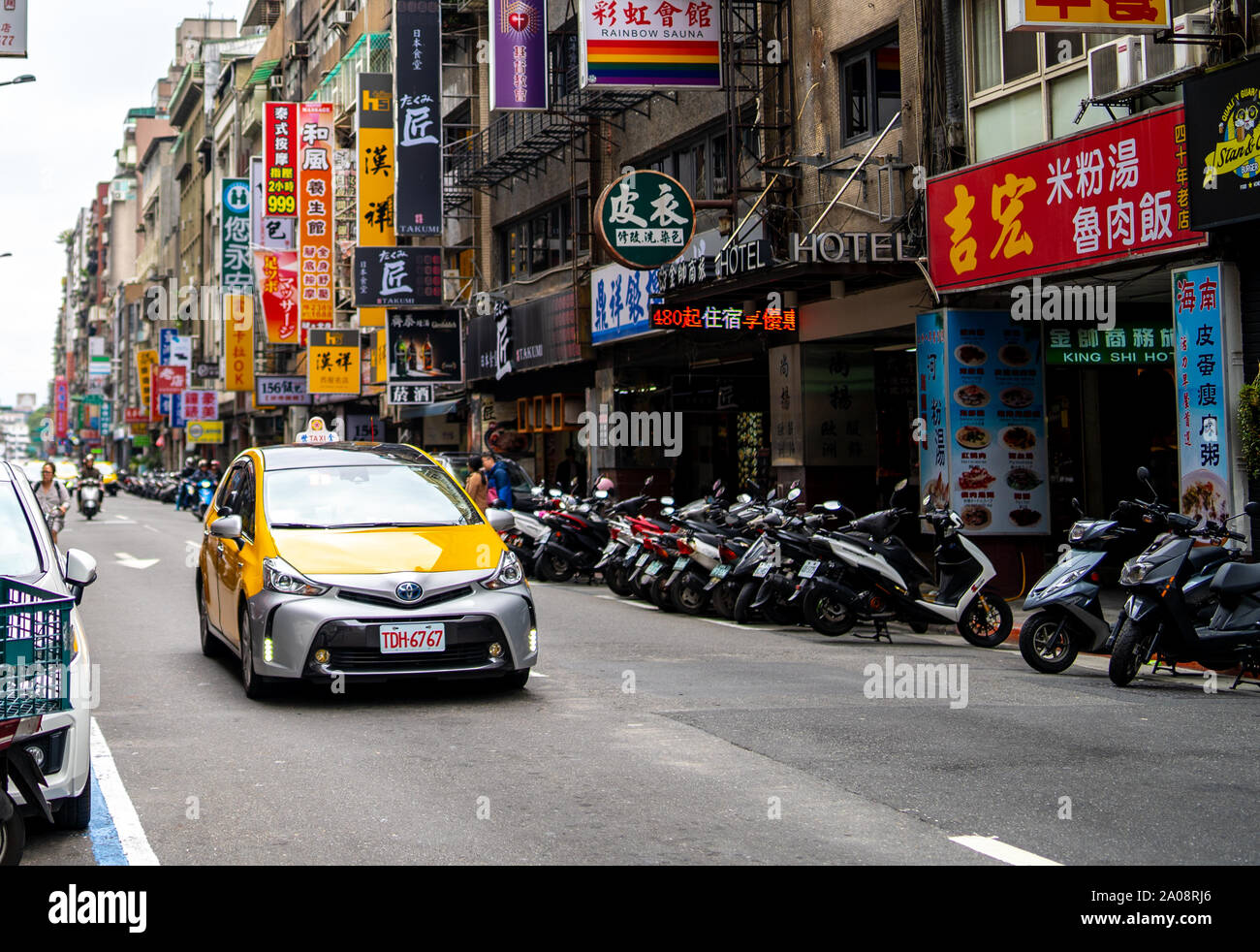 Taipei, Taiwan: Yellow Taiwanese Taxi on small urban street in Taipei with many chinese advertisement street signs. Stock Photo