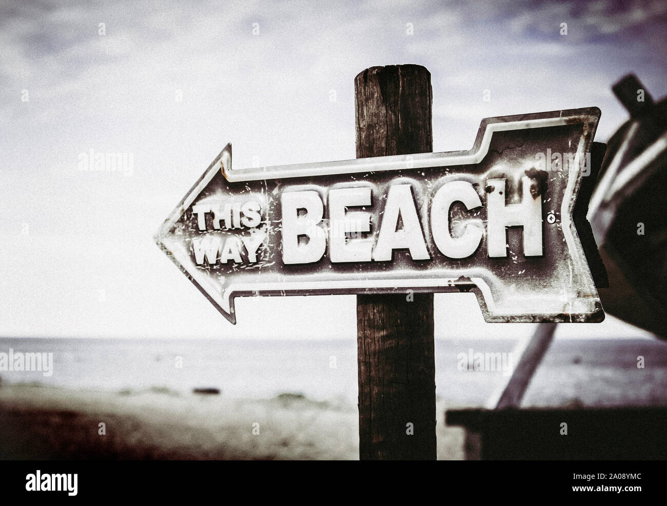 Vintage artistic color arrow shaped sign showing way to the beach, on the pole on the beach, sea background. Stock Photo