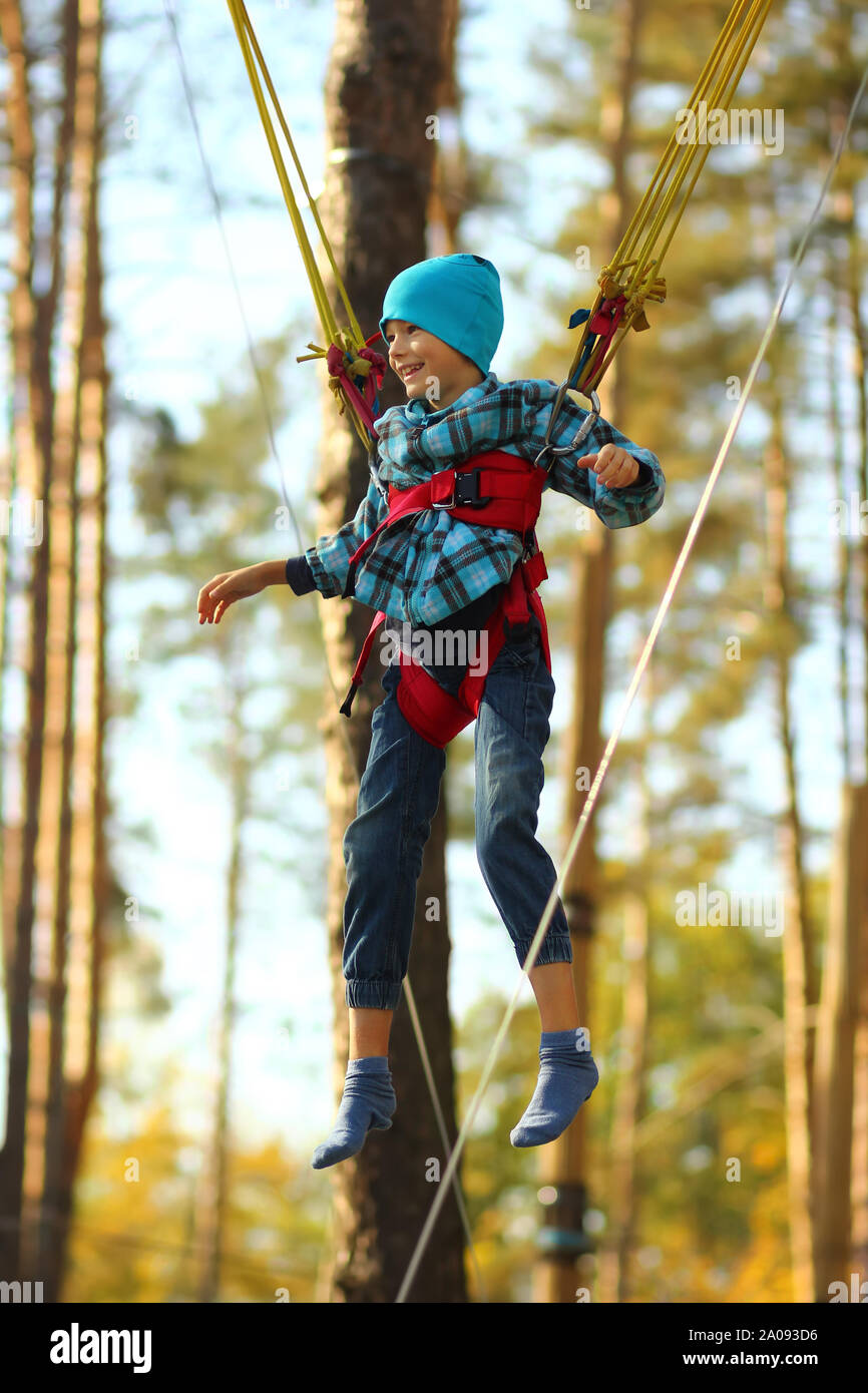Boy jumping on a bungee trampoline and flying in the air in the autumn park outdoor Stock Photo