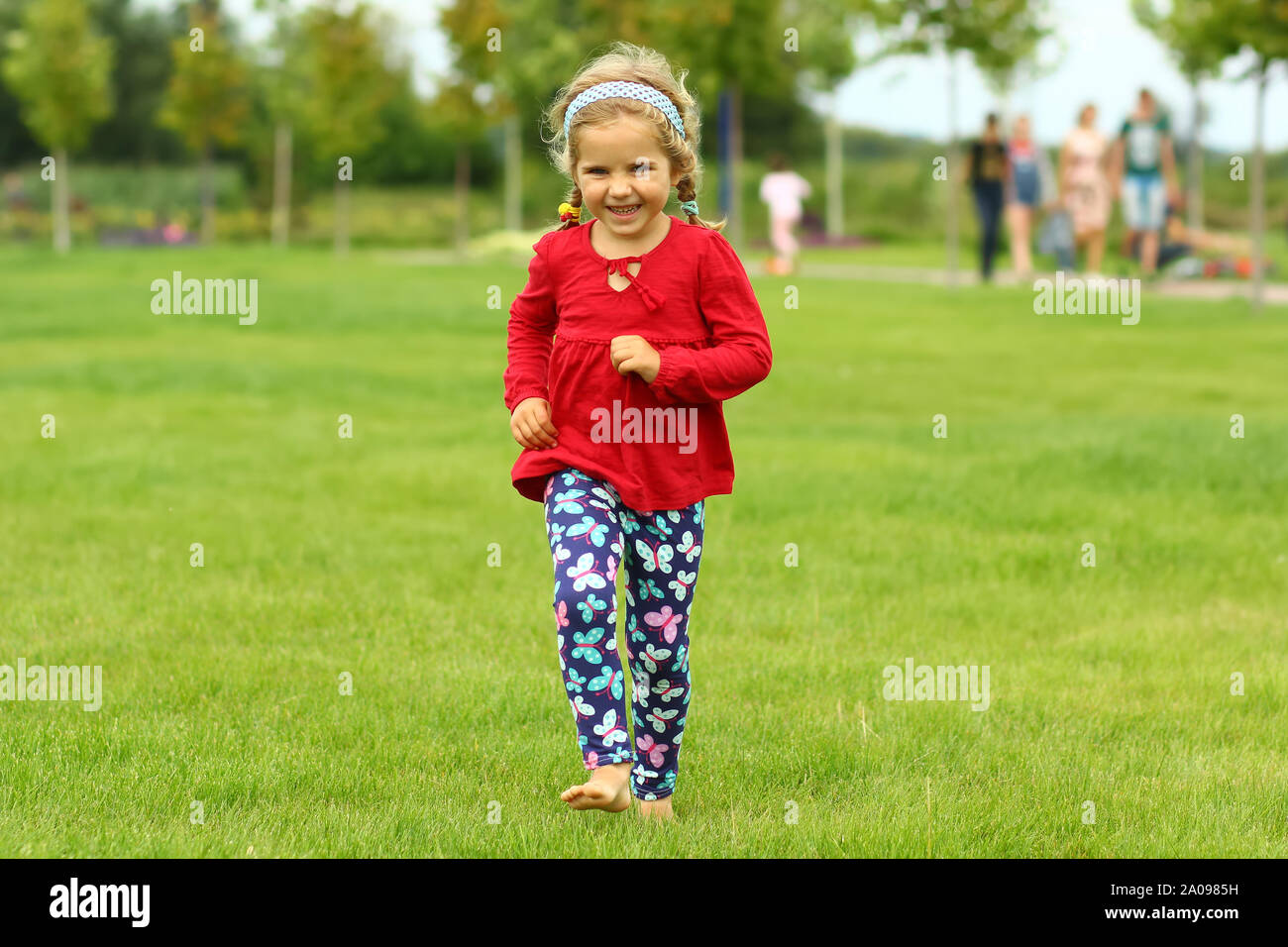 Toddler caucasian girl running barefoot on the lawn outdoors Stock Photo