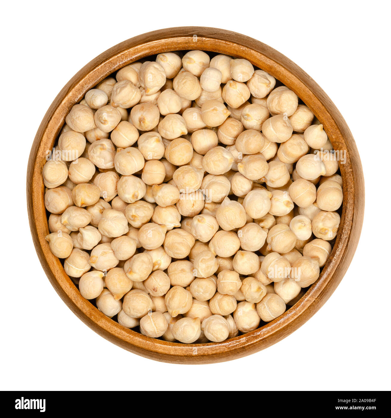Dried chickpeas in wooden bowl. Light tan Kabuli chickpea variety. Chick peas, Cicer arietinum, high protein legume and ingredient of hummus. Stock Photo