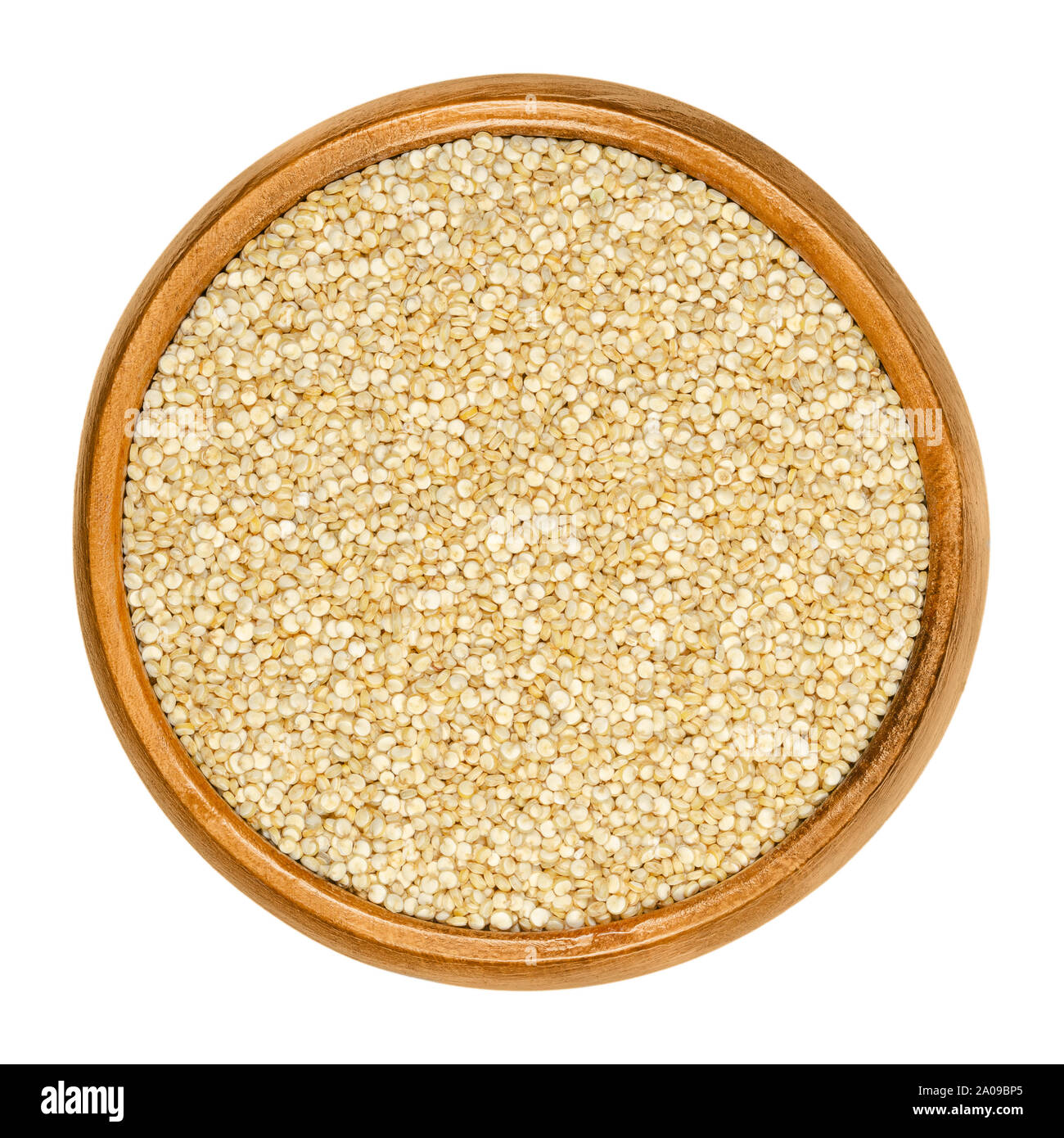 White quinoa in wooden bowl. Raw dried seeds of Chenopodium quinoa, a gluten-free pseudocereal, originated in the Andean region. Closeup, from above. Stock Photo