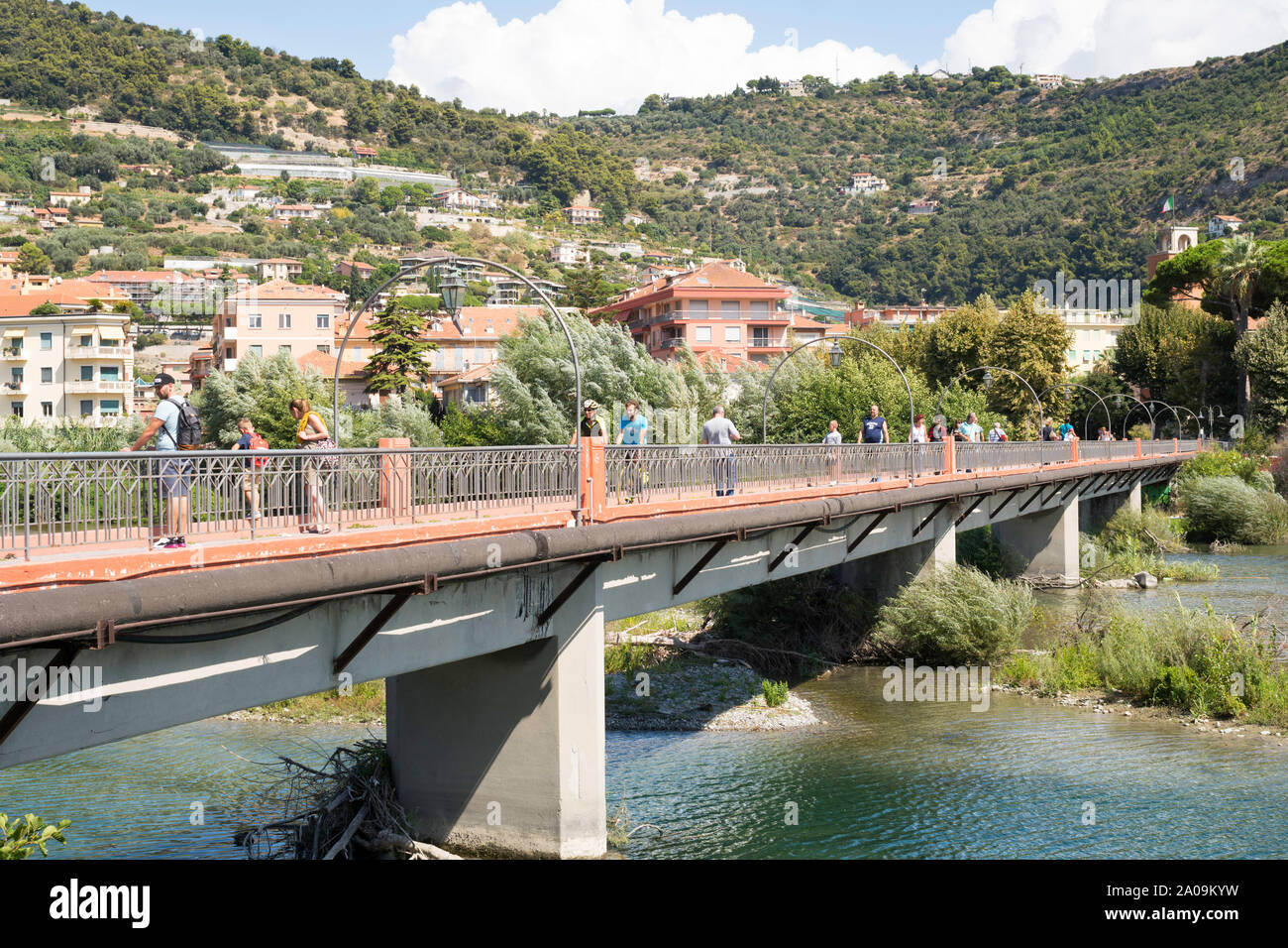 People walking and cycling over the Passerella Squarciafichi footbridge spanning the river Roia in Ventimiglia, Liguria, Italy, Europe Stock Photo