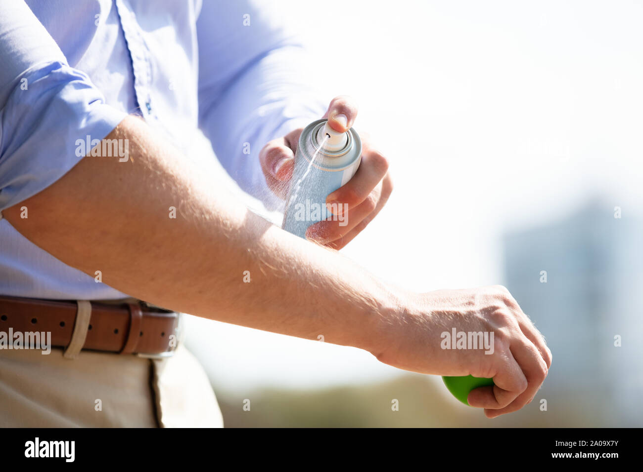 Man Spraying Anti Insect Deet Spray On Skin Over His Arm Outdoors Stock Photo