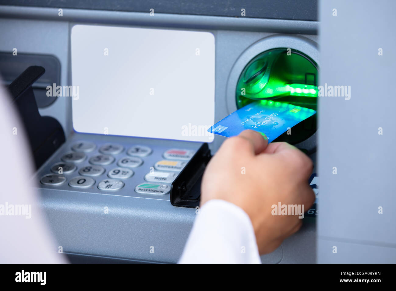 Close-up Of A Person's Hand Insert Card Into ATM Machine Slot To Withdraw Money Stock Photo