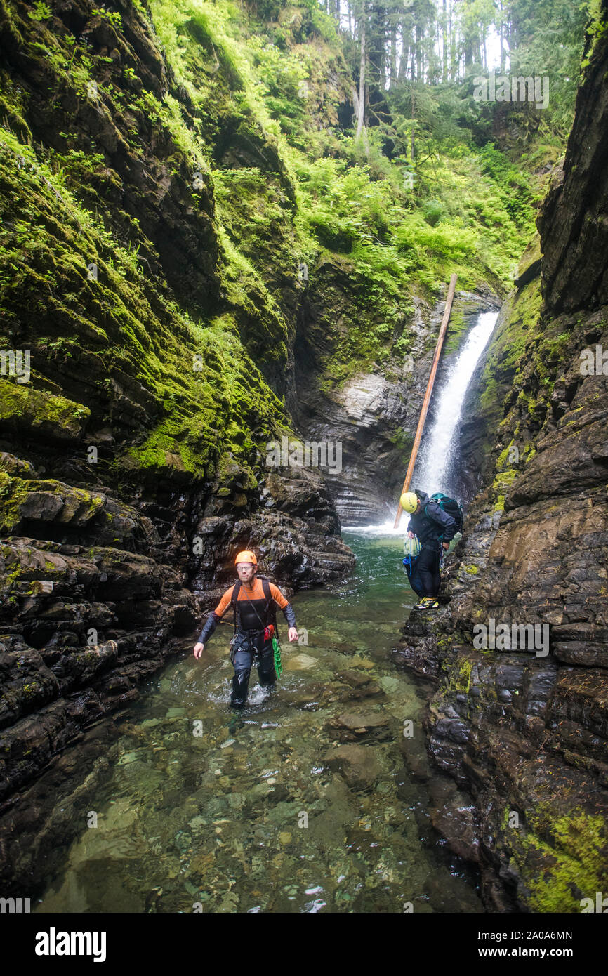 Two men walk through a shallow section of river after rappelling Stock Photo