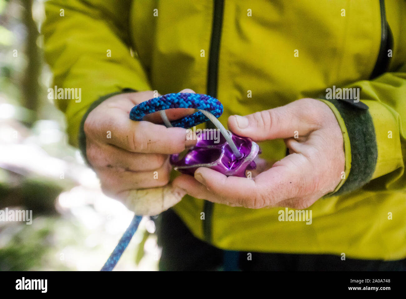 detail of man running rope through a belay device Stock Photo Alamy