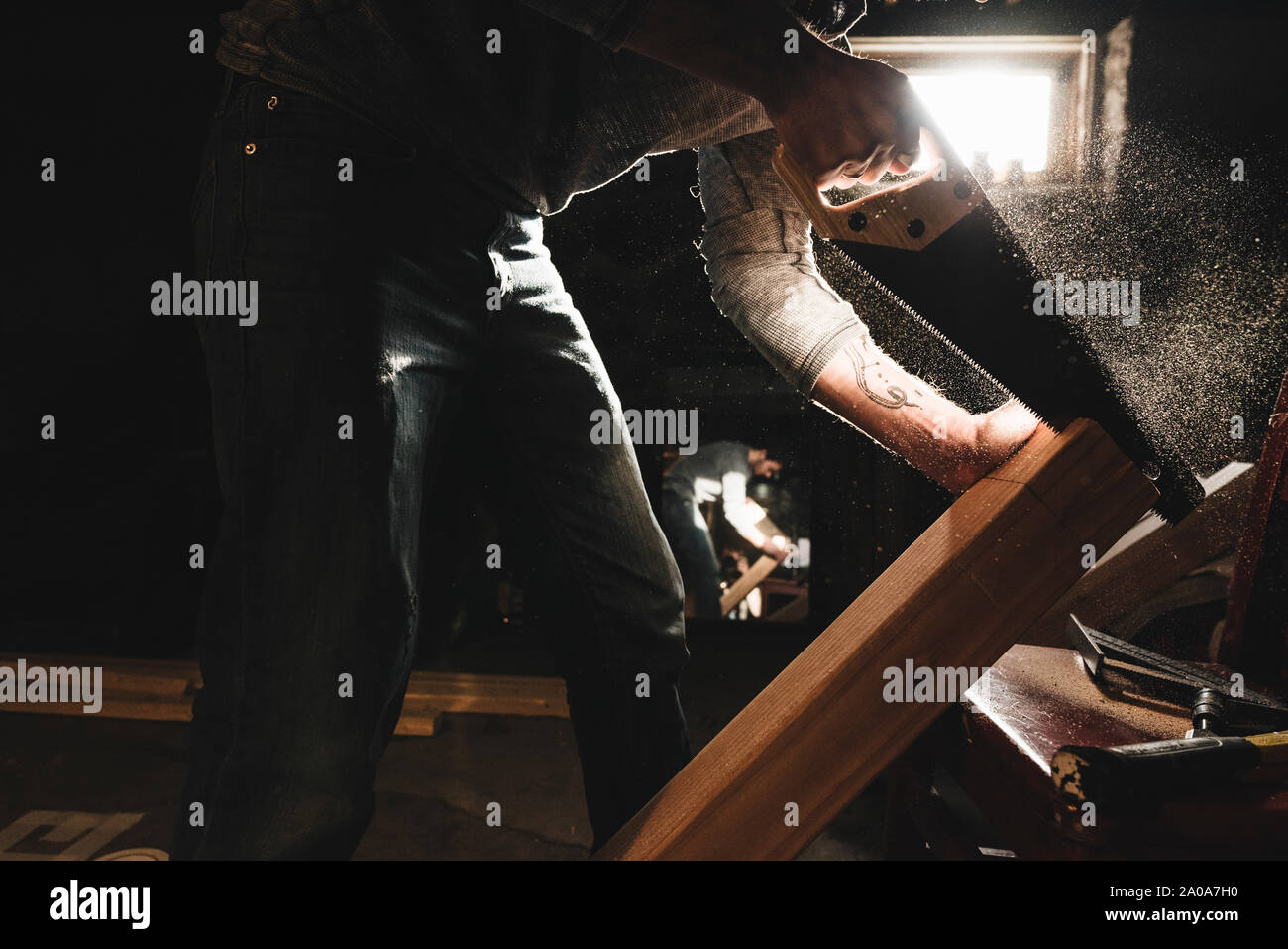 Young Man Saws Wood in Workshop Stock Photo