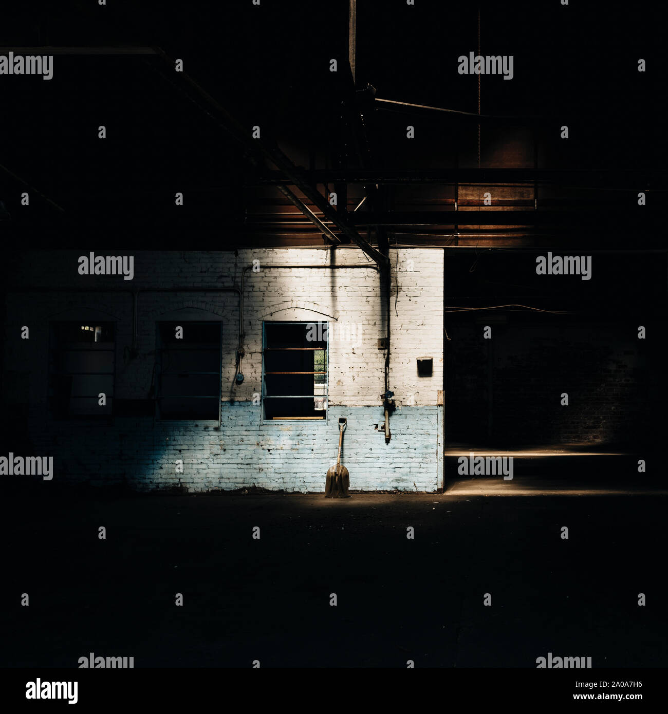 Shovel Leans Against Wall in Abandoned Warehouse Stock Photo