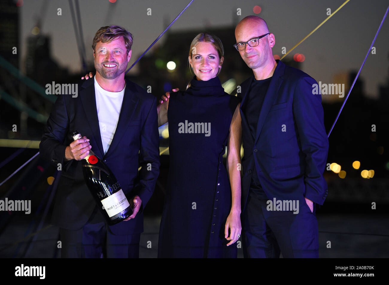 (left to right) Yachtsman Alex Thomson, Poppy Delevingne and Hugo Boss CEO Mark Langer at the christening ceremony for the Hugo Boss yacht in London. Stock Photo