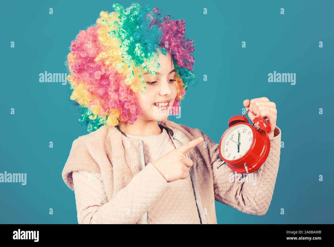 Its resting time. Happy little girl with colorful wig hair pointing at