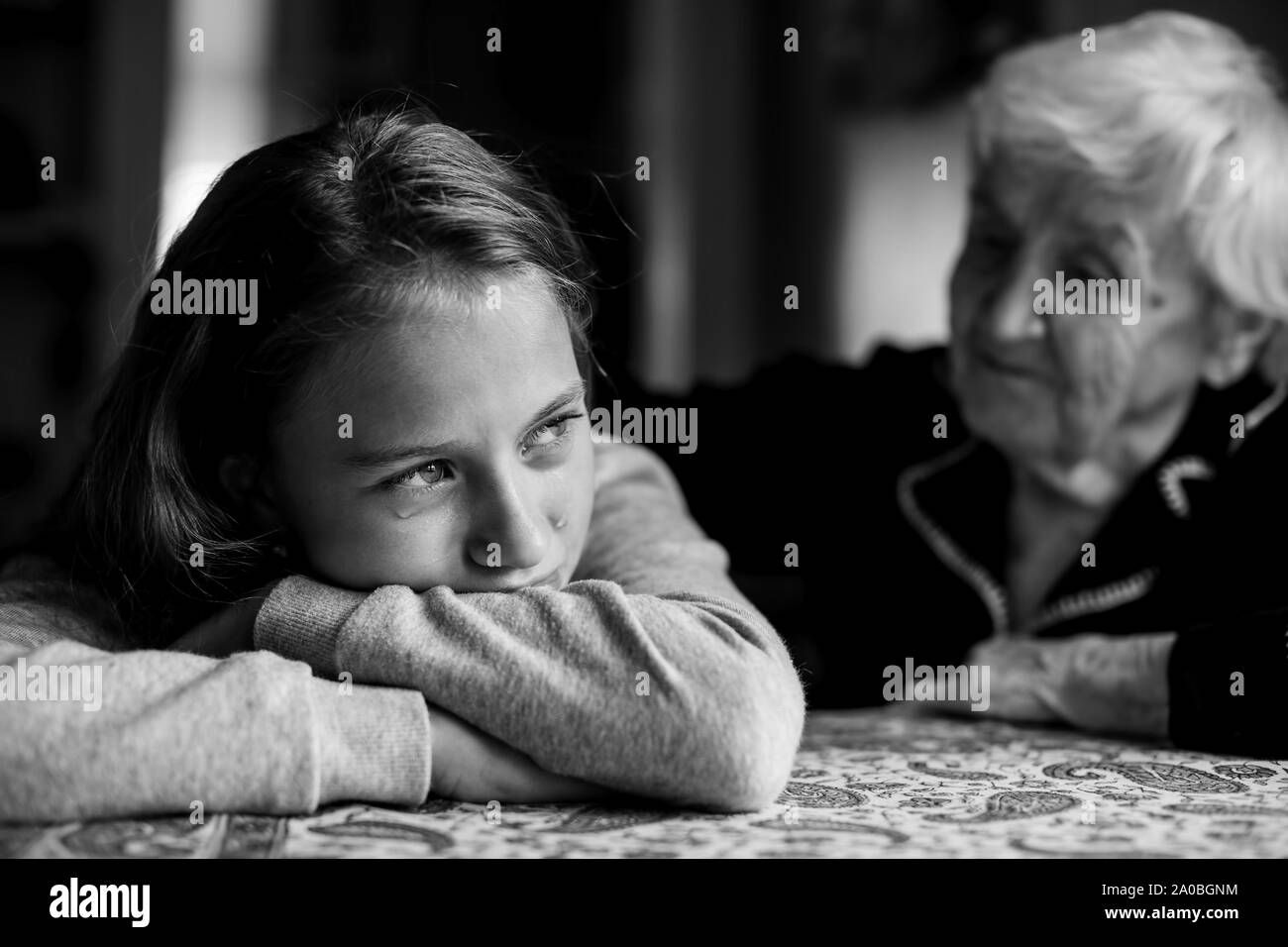 A crying little girl is comforted by her grandmother. Black and white photo. Stock Photo
