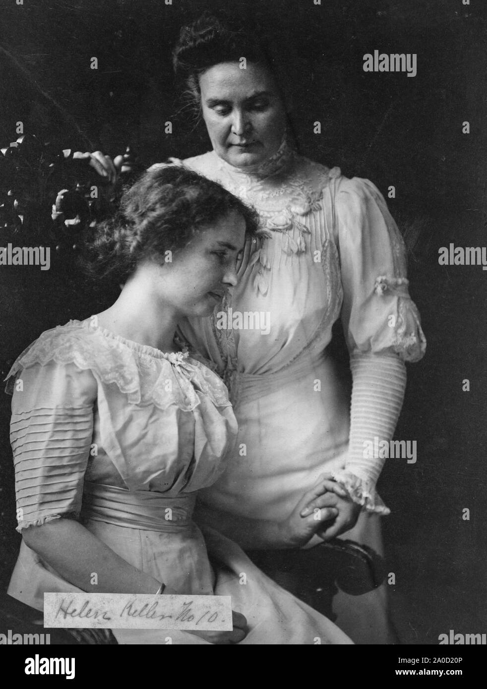 Helen Keller - seated - holds the hand of her teacher, Anne Mansfield Sullivan. Stock Photo