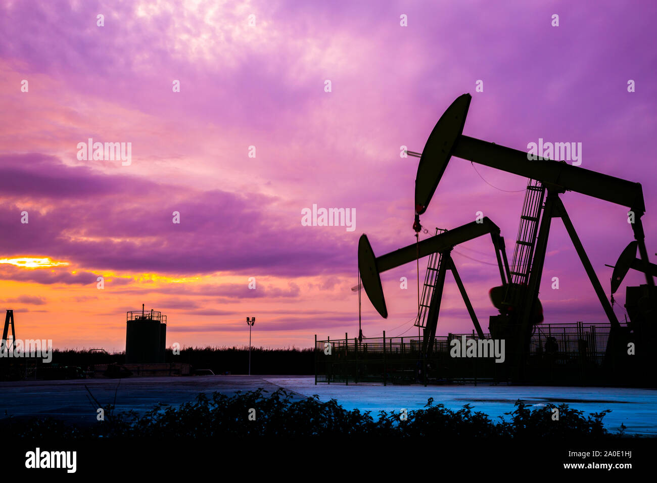 Silhouette of Oil pumps at oil field with nice sunset sky background