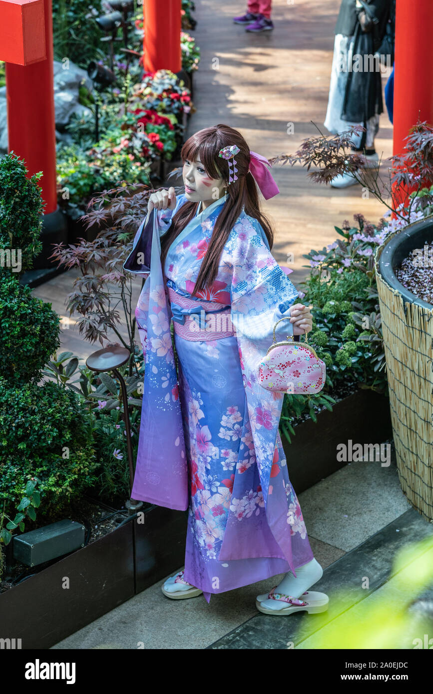 Singapore - March 22, 2019: Gardens by the Bay, the Flower Dome. Young Japanese woman poses in light blue and pink Kimono close to red Torii and near Stock Photo