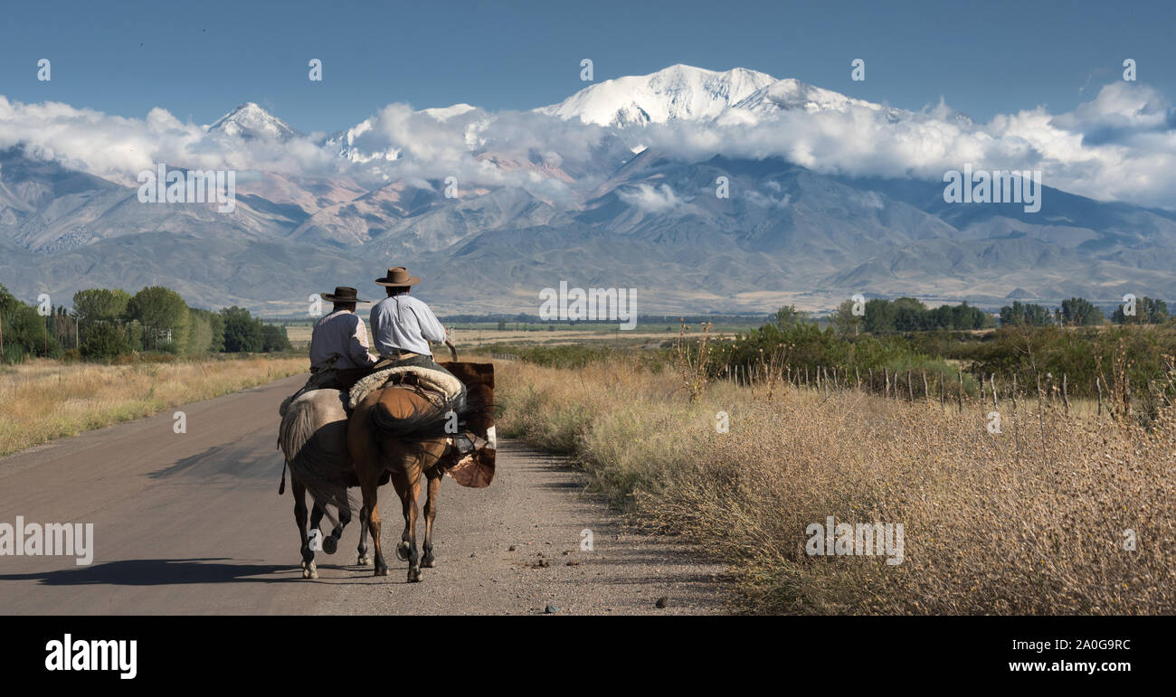 Typical gauchos riding horses near to the Andes mountains Stock Photo