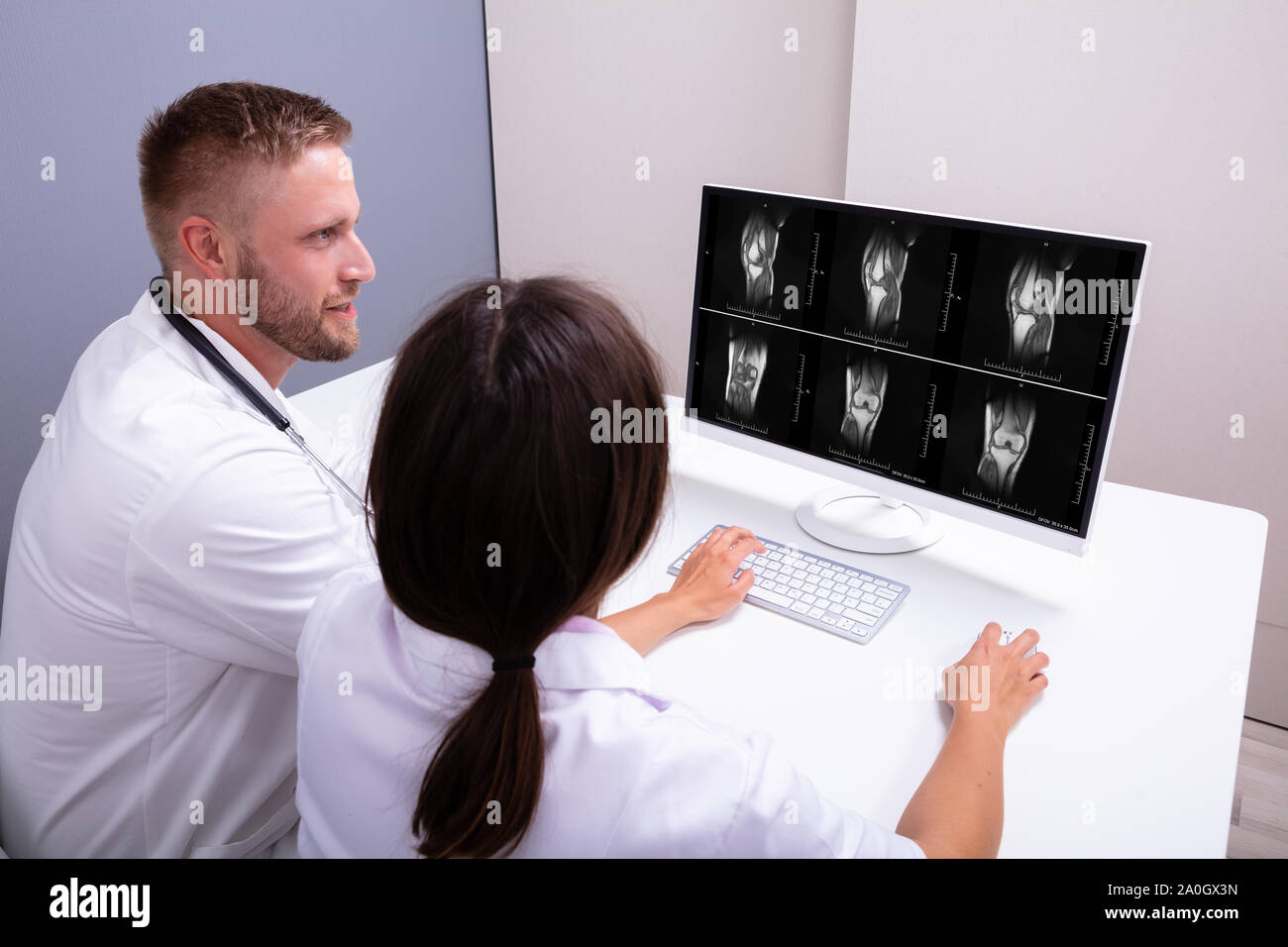 Doctors Looking At An MRI Scan At Computer In Clinic Stock Photo