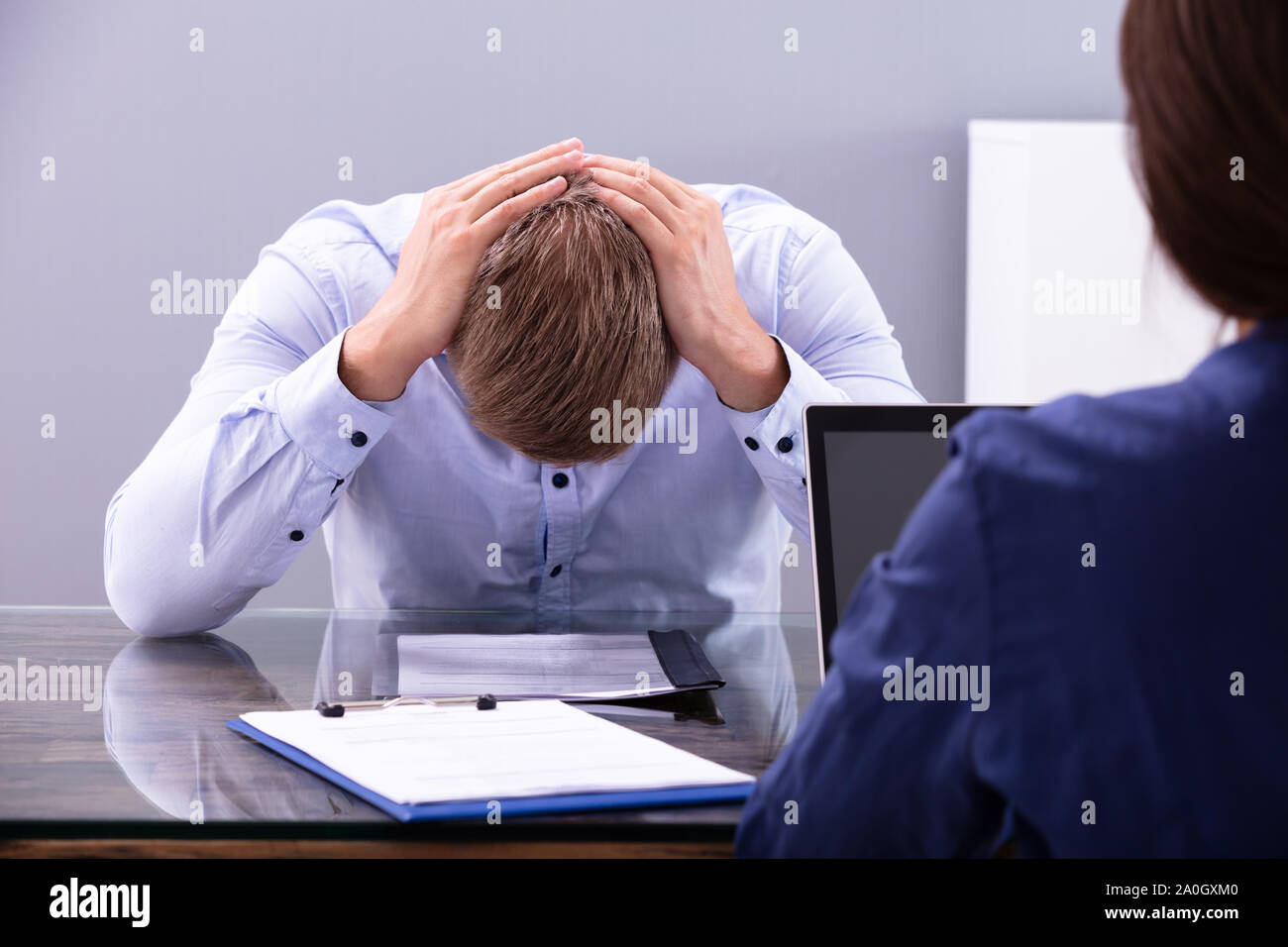 Stressed Young Business Man Holding His Head At Interview In Office Stock Photo