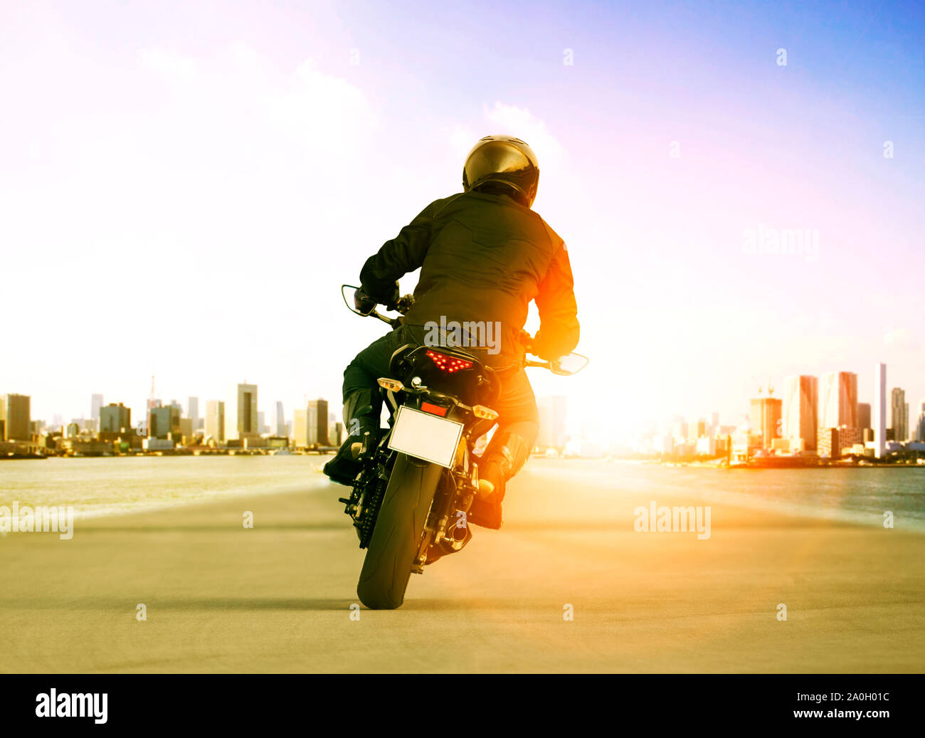 rear view of man riding motorcycle on urban traffic road for people ...