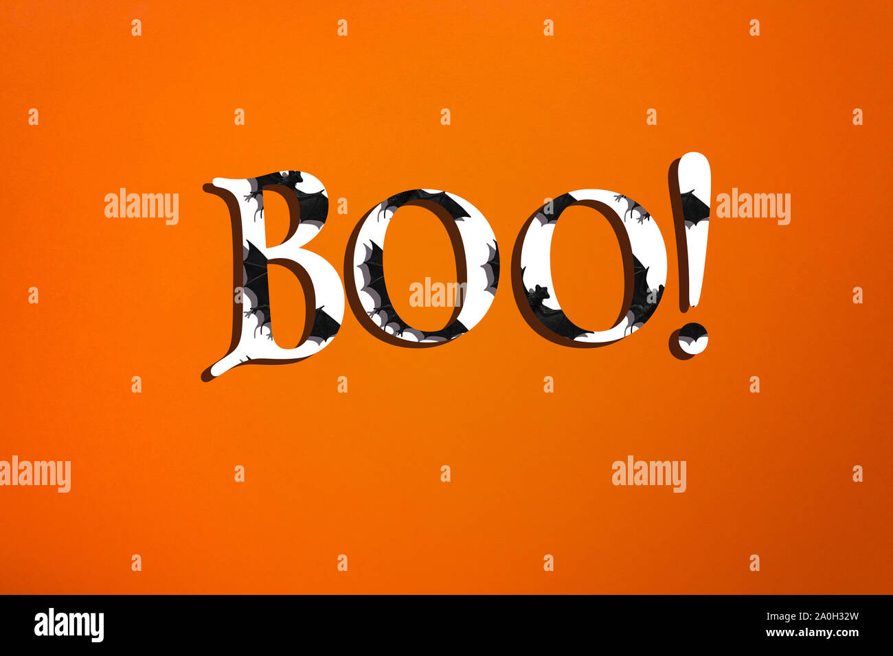 Creative minimalistic halloween text on orange background. White letters with bats and shadows. Stock Photo