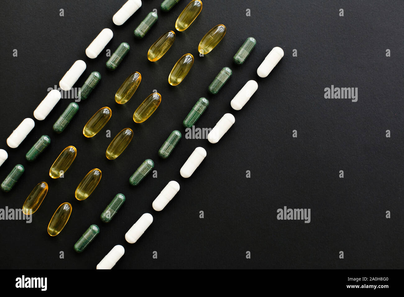 Dietary supplements. Omega 3, spirulina, chlorophyll,magnesium capsules on black dark background, flat lay. Vitamin pills. Health support and treatme Stock Photo