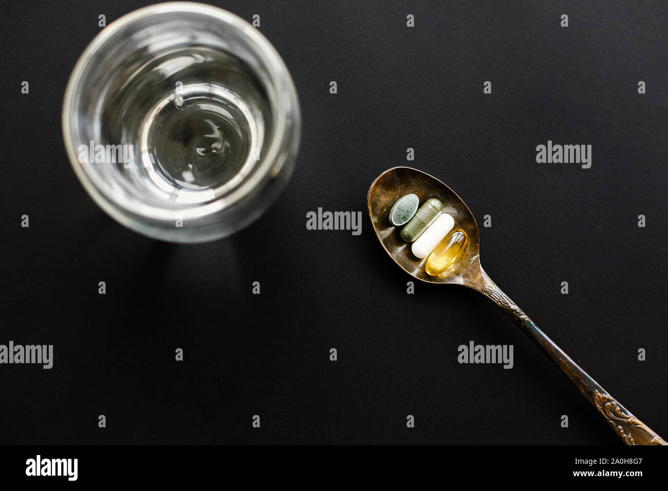 Omega 3, spirulina, chlorophyll, magnesium capsules on spoon and glass