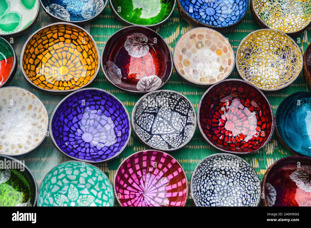 Top view of colorful handmade lacquered bowls made from coconut shells and sold as souvenirs in the local market of Luang Prabang, Laos Stock Photo