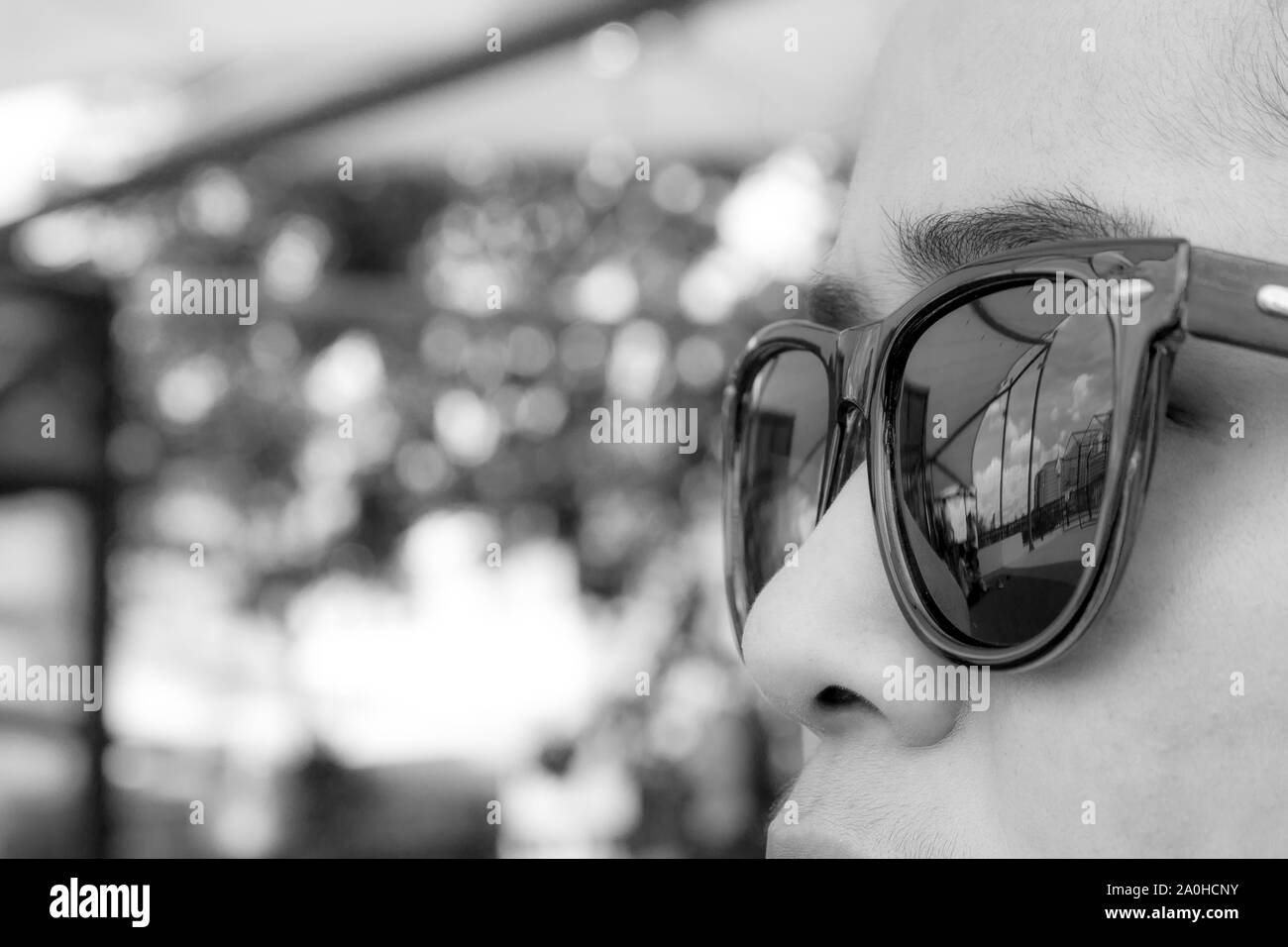Black and white face woman wearing brown sunglasses are looking for the city and the sky in the daytime. Stock Photo