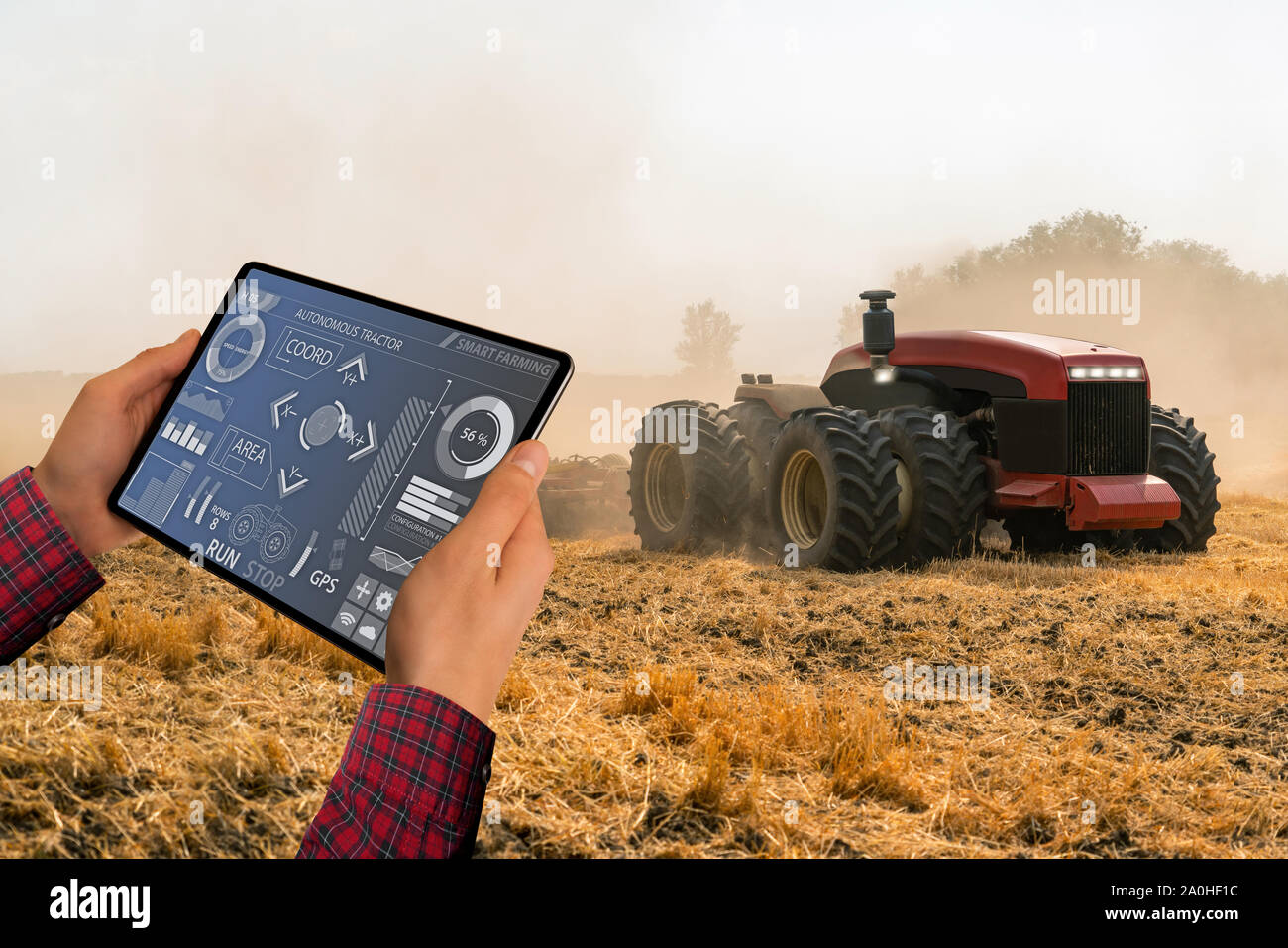 A farmer with digital tablet controls an autonomous tractor on a smart farm Stock Photo